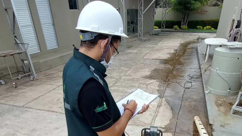 Técnico fazendo anotação em um prancheta próximo de poço em uma empresa de esterilização.