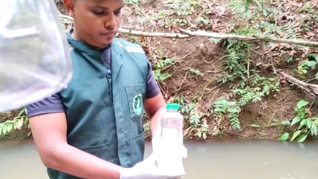 Engenheiro Ambiental realizando coleta de recurso hídrico em área do córrego para análise de qualidade de água ao redor da vegetação local.